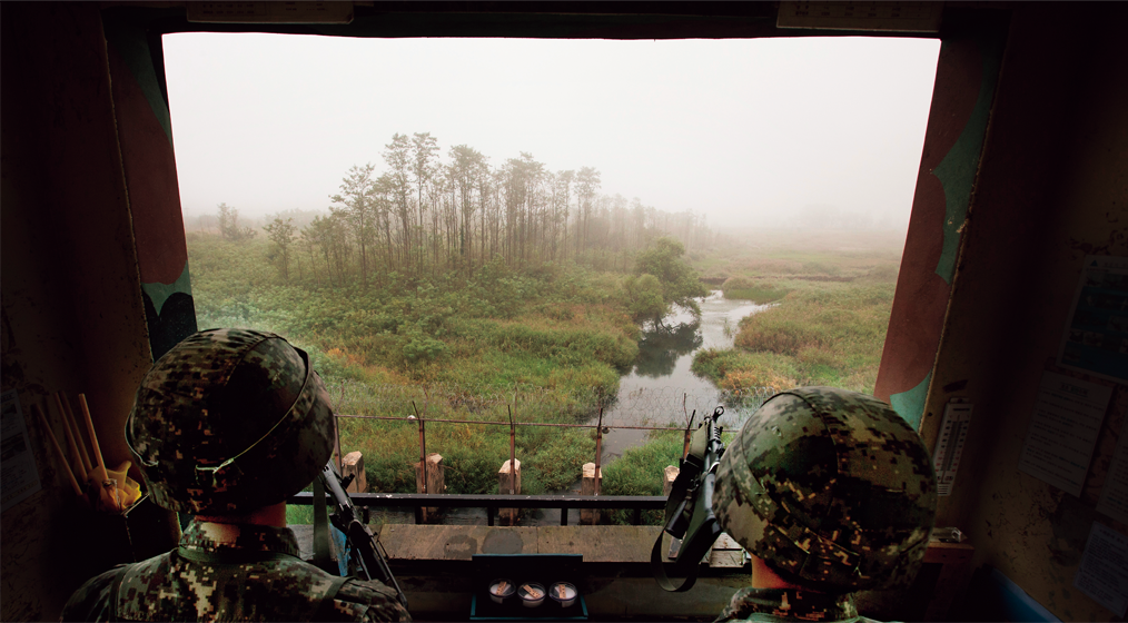 중부전선 최전방경계초소(GP)에서 육군 장병 두 사람이 비무장지대를 내려다보며 경계 근무를 서고 있다. Hai binh lính nhìn xuống Khu vực phi quân sự từ một đồn gác ở mặt trận trung tâm.