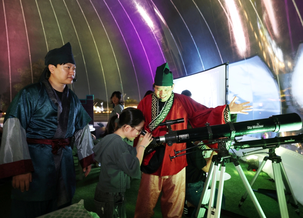 ▲ 16일 경북 경주 첨성대 옆 체험존에서 '아, 신라의 밤이여' 프로그램 참가자들이 별자리를 찾으며 신라의 천문 문화를 경험하고 있다. Ngày 16, khách tham gia chương trình “Ôi, đêm Silla” đang tìm kiếm chòm sao và trải nghiệm văn hóa thiên văn Silla tại khu trải nghiệm bên cạnh Cheomseongdae, Gyeongju.