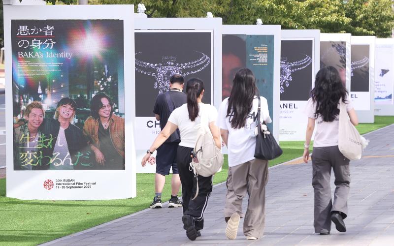 ▲ 17일 부산 해운대구 영화의전당 일대에서 시민들이 부산국제영화제 홍보물 옆을 지나가고 있다. Các biển quảng cáo đứng về Liên hoan phim Quốc tế Busan (BIFF) lần thứ 30 được lắp đặt ở Trung tâm Điện ảnh Busan, quận Haeundae-gu, thành phố Busan vào ngày 17/9/2025. (Ảnh: Yonhap News - 연합뉴스)