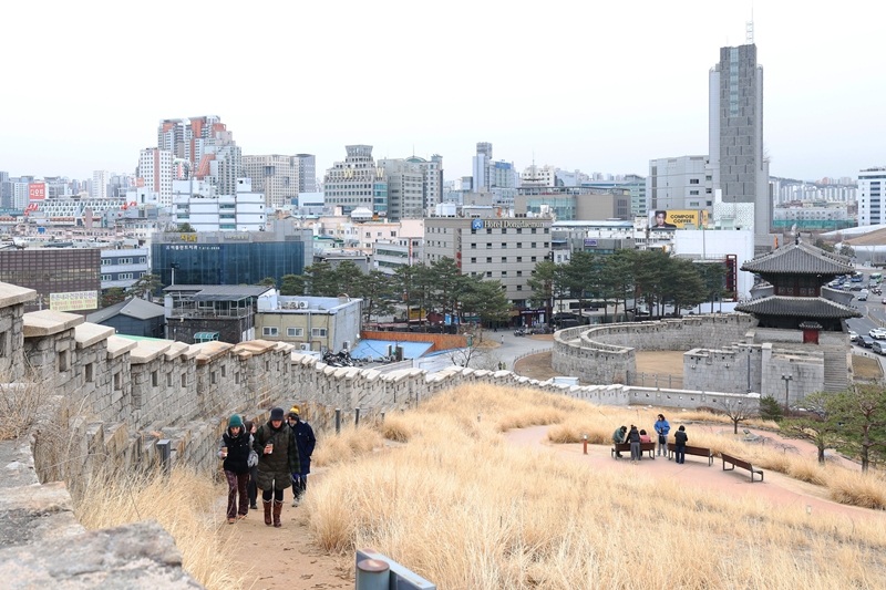 ▲ 14세기에 축조된 한양도성은 조선의 수도 한양을 방어하던 성곽이다. 오늘날에는 서울 도심 속 역사 유산이자 시민과 관광객이 즐겨 찾는 탐방 코스로 자리매김하고 있다. 사진은 한양도성 낙산 구간을 걷고 있는 외국인 관광객들. Thành Hanyang, được xây dựng vào thế kỷ 14, là một tường thành bảo vệ kinh đô Hanyang của Triều đại Joseon. Ngày nay công trình này trở thành một di sản lịch sử giữa lòng thành phố Seoul, là tuyến tham quan được người dân và du khách yêu thích. Ảnh chụp du khách nước ngoài đang đi dạo ở đoạn Naksan của tường thành Hanyang..